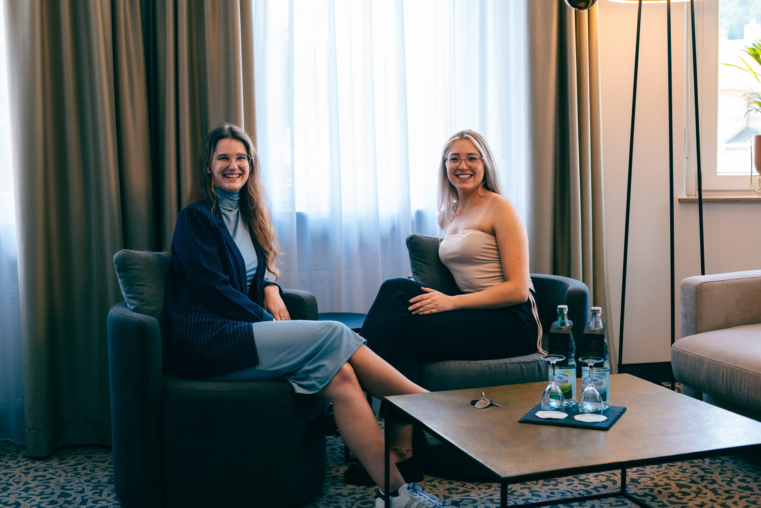 zwei Geschäftsfrauen sitzend auf Lounge Sesseln in Hotelzimmer